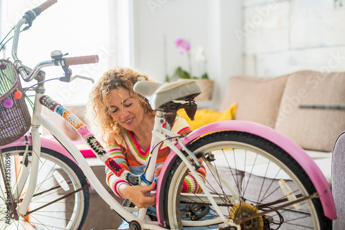 Beautiful caucasian young woman modifying a bike at home with handcrafted tailors art materials - people and colors with crazy art lifestyle - happiness working handmade photo