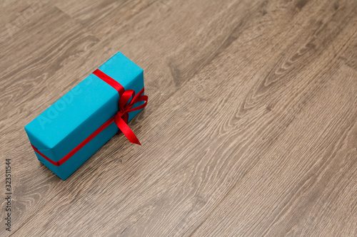 A smartphone in a blue gift box with a red ribbon lies on a wooden background. A gift for a holiday in a beautiful package. A sign of attention to a loved ones on their birthday. Selective focus