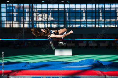 Woman jumping over bar at athletics meeting