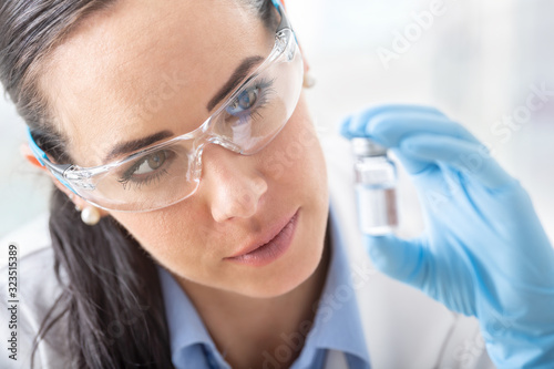 A young female scientist is researching a chemical substance using protective glasses and hygienic gloves