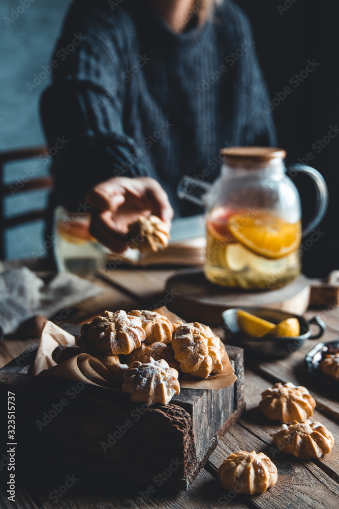 A woman reaches for a cake and drinks grapefruit tea. Healthy drink.