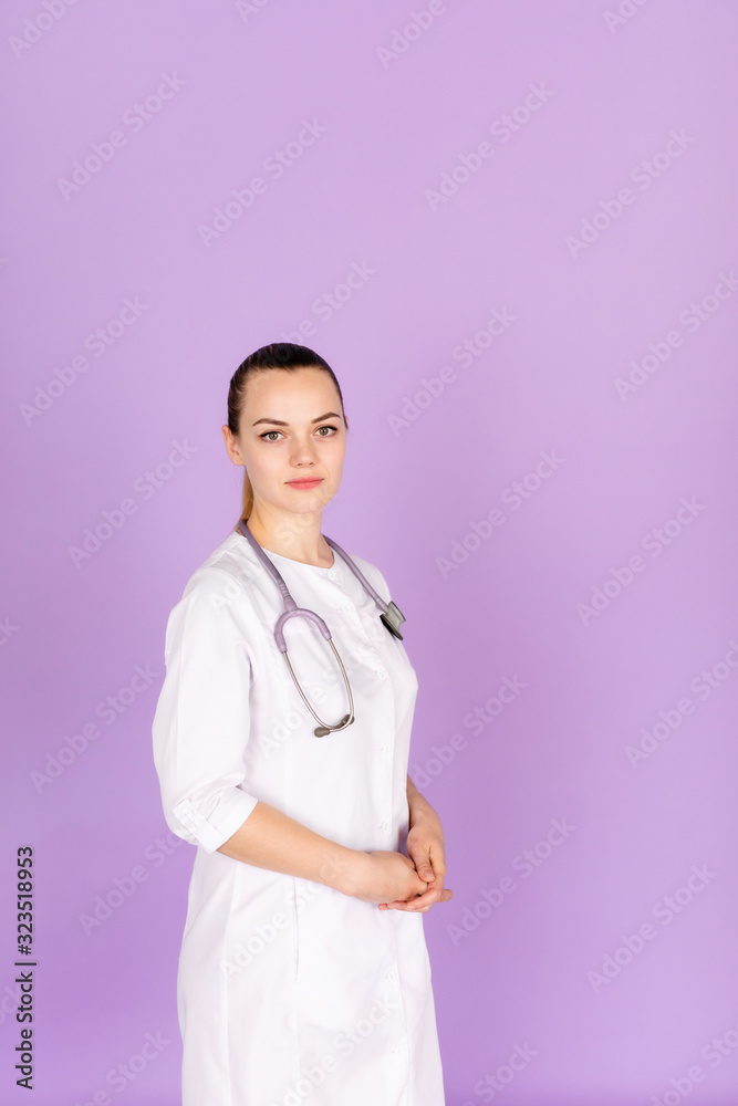 Medical concept of beautiful female doctor in white coat with phonendoscope. Medical student general practitioner. Woman hospital worker looking at camera and smiling, studio, purple background. Medical concept of beautiful female doctor in white coat with phonendoscope. Medical student general practitioner. Woman hospital worker looking at camera and smiling, studio, purple background.