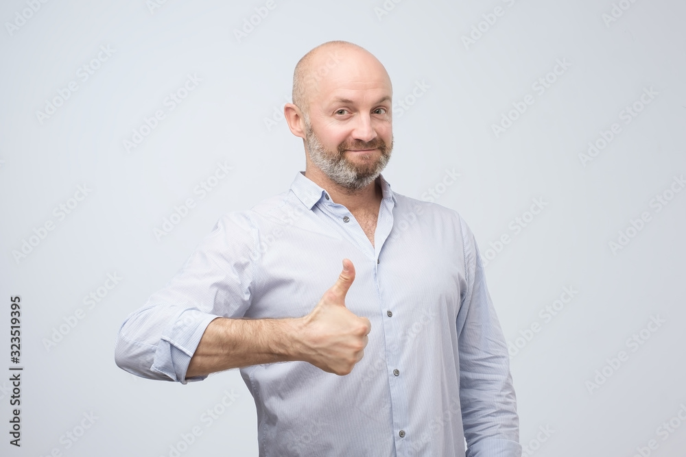 Happy caucasian man with thumbs up gesture, approving your choice. isolated on white wall.