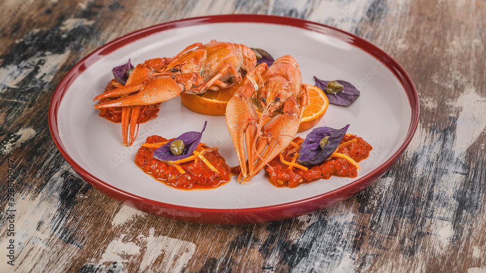 Food banner. Boiled crayfish. Delicacy with chili pepper sauce, orange, zest, basil and capers on a plate. Haute cuisine Food banner. Boiled crayfish. Delicacy with chili pepper sauce, orange, zest, basil and capers on a plate. Haute cuisine