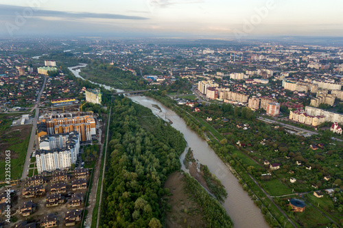 Aerial view of Ivano-Frankivsk city with residential area and suburb houses with a river in middle. © bilanol