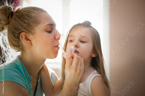 Mother using "Nose cleaner vacuum suction nasal mucus runny aspirator kids inhalation" to pull out the snot from nose. Little Girl has been sucking snot from running nose symptom by her mother.