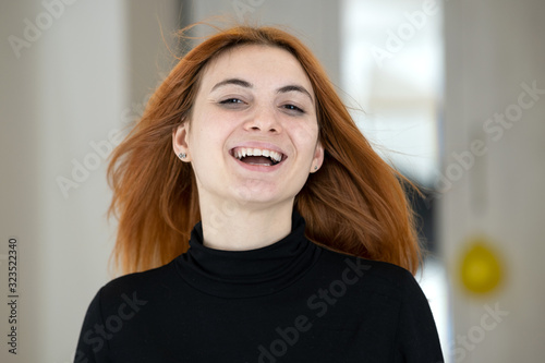 Close up portrait of pretty redhead girl with long wavy hair blowing on the wind.