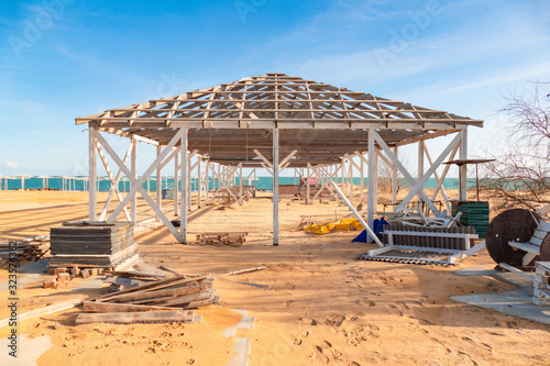 Unfinished wooden structure for canopy in the tourist resort on beach by the sea in off-season
