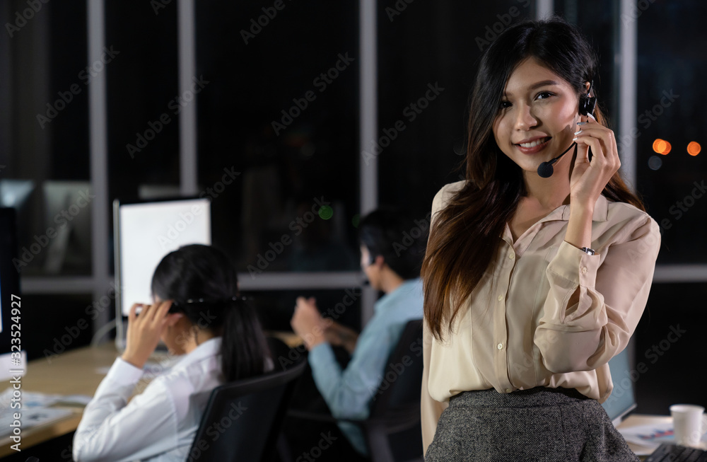 Young beautiful smiling call center staff talking and provide services to customers via headphones and microphone cable with his colleague team as customer service. Young beautiful smiling call center staff talking and provide services to customers via headphones and microphone cable with his colleague team as customer service.