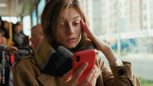 Woman use phone coughs into handkerchief sneezes on the tram look at camera cold autumn day flu season disease fever grippe health illness infection influenza migraine sickness slow motion