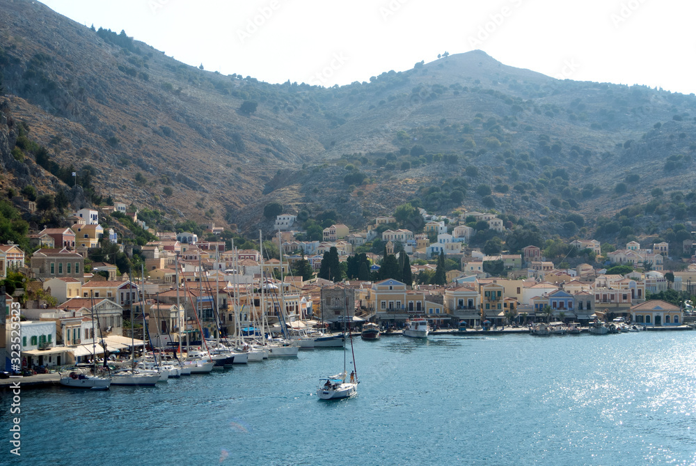 The harbour on the beautiful Greek island of Symi.  Neo classical houses are seen on both sides of the bay, on the steep hillsides.