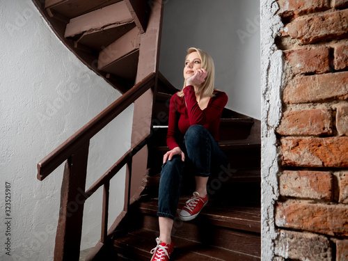 blonde hipster sits on aged stairs in old country house photo