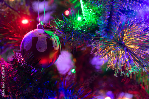 Obraz na płótnie A close up photograph of a Christmas pudding bauble hanging from a green Christmas tree surrounded with multicoloured fairy lights w salonie
