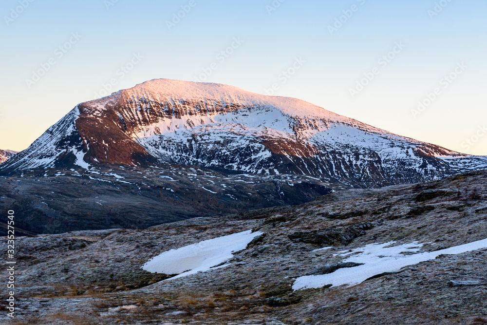 A photograph of the snow covered top of Nordfjellet lit by the setting sun