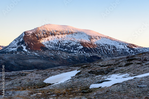 Obraz na płótnie A photograph of the snow covered top of Nordfjellet lit by the setting sun w salonie