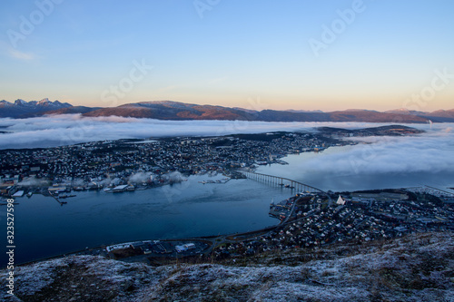 Obraz na płótnie A beautiful cityscape of Tromso (including the Artic Cathedral) partly covered by cloud taken from Fløya during sunset w salonie