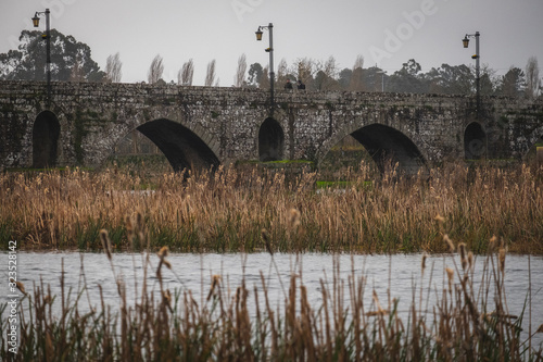 Antiga ponte de pedra com arcos sobre o rio e pantano photo