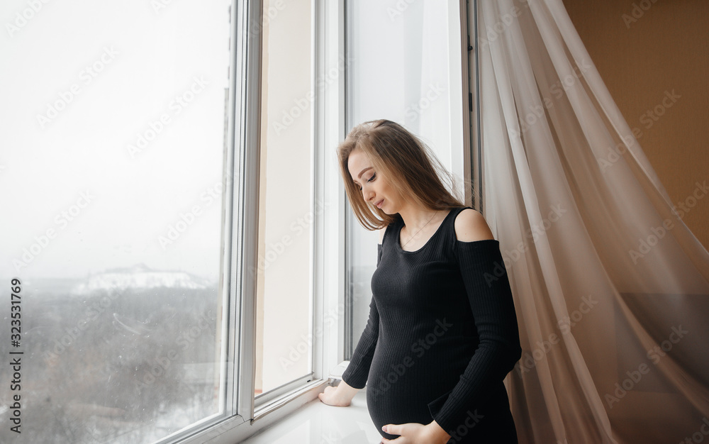 A pregnant girl is breathing fresh air from the window A pregnant girl is breathing fresh air from the window