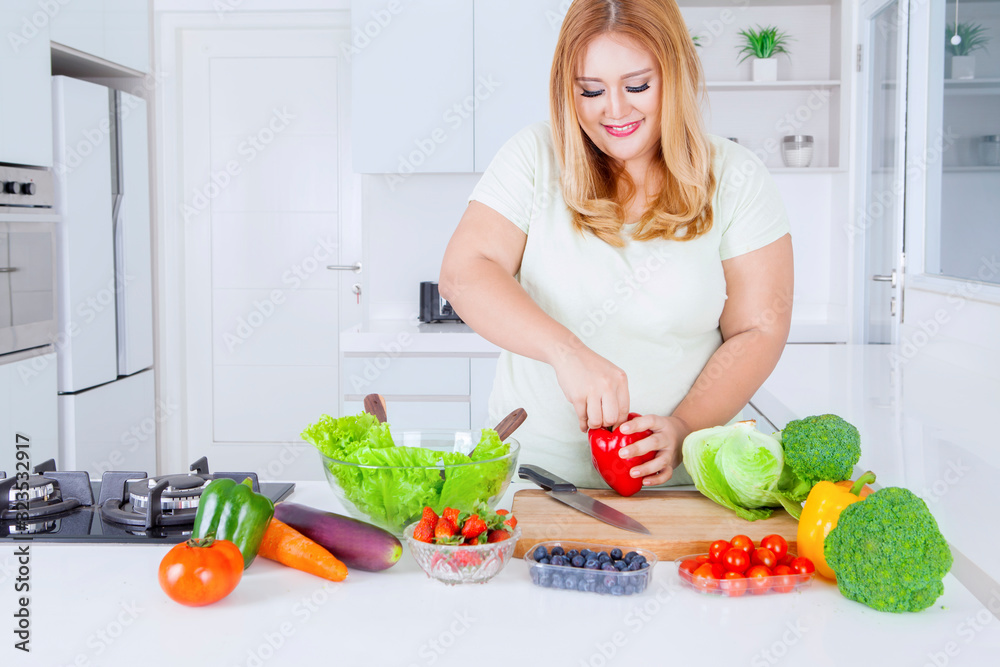 Blonde overweight woman preparing fresh vegetable