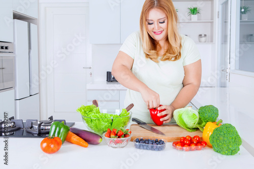 Blonde overweight woman preparing fresh vegetable