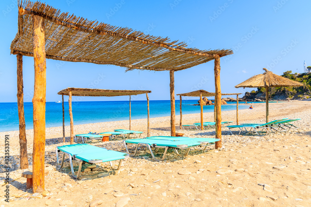Sunbeds on Potami beach and blue sea, Samos island, Greece