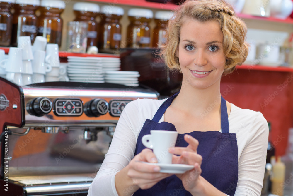 young female barista holding cup of cappuccino
