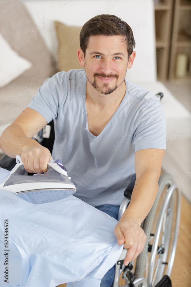 happy disabled man on wheelchair ironing clothing happy disabled man on wheelchair ironing clothing
