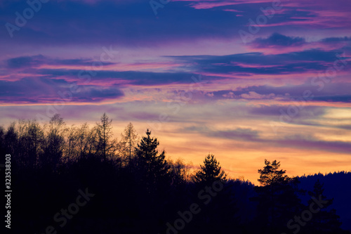 Landscape Picture of the dramatic or romantic red sky clouds over the deep forest or wood during the winter sunset in the highland part of Czech Republic. Beautiful part of country for holliday.