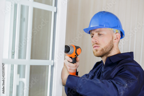 construction worker using drill to install window