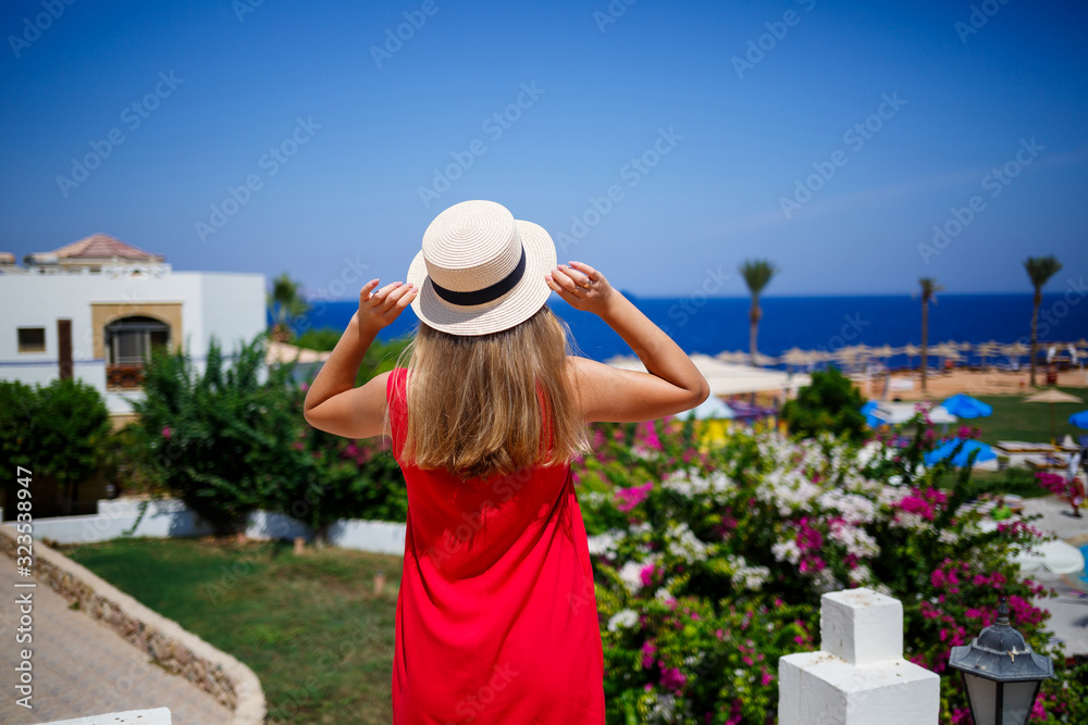 Beautiful girl in red dress and hat in the bright sun
