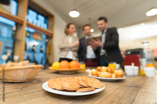 snacks on table in foreground businesspeople with tablet in background photo