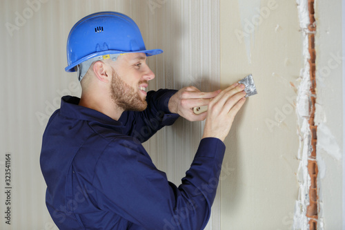 Fotografie young amle labourer preparing wall with scraper
