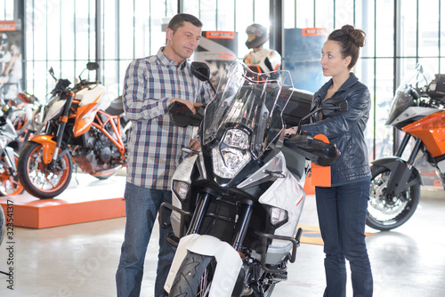 man and woman by motorcycle in showroom