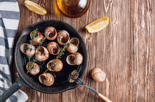 Bourgogne Escargot Snails with herbs butter in iron pan on rustic wooden background. Top view