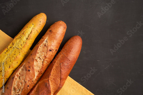 Three crispy french baguettes lie on an old wooden table with free space for text