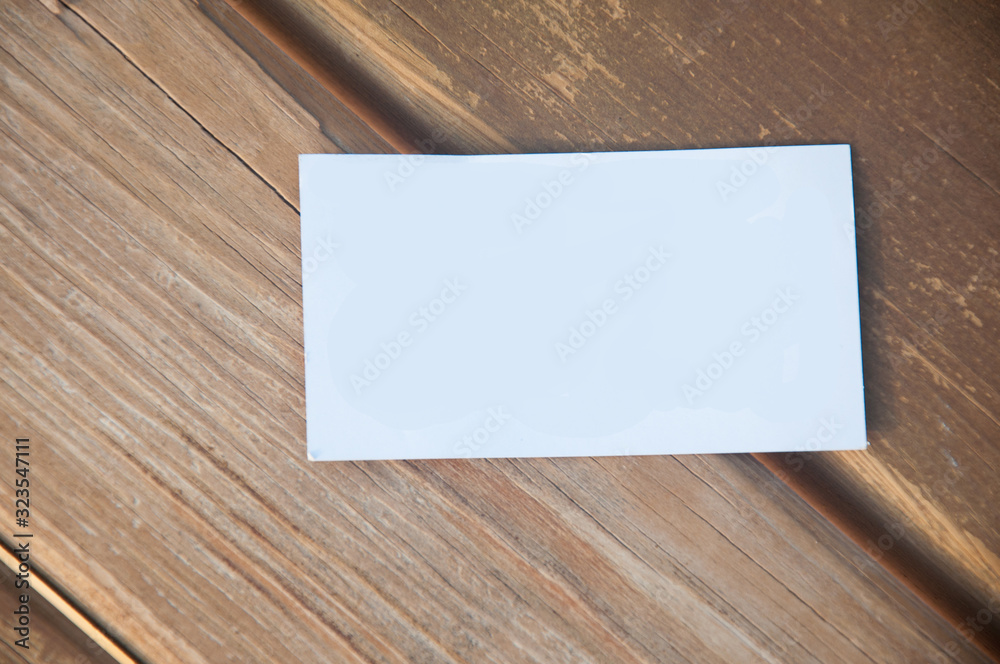Empty white paper business card lying on wooden desk background. Top view, copy space for text Empty white paper business card lying on wooden desk background. Top view, copy space for text