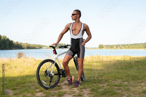 A man with a bicycle in nature, in a field.