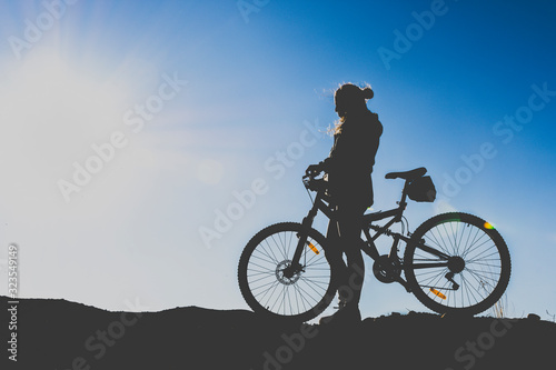 silhouette of a sports girl who goes by bicycle