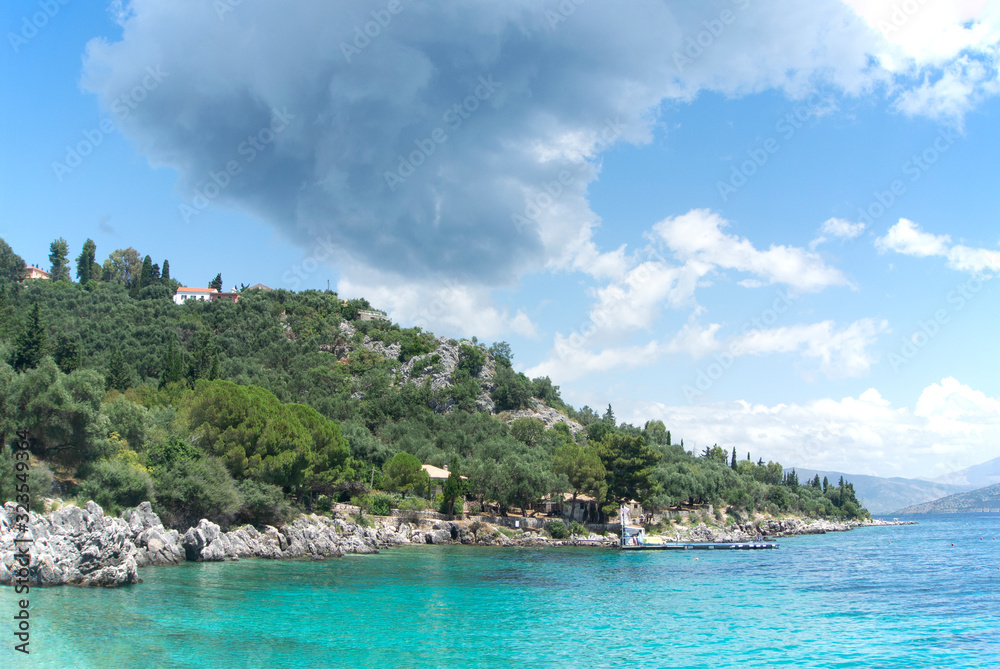 The rocky shoreline at Nisaki on the beautiful island of Corfu in Greece.   Pine clad hills set against the deep blue Ioanian sea.