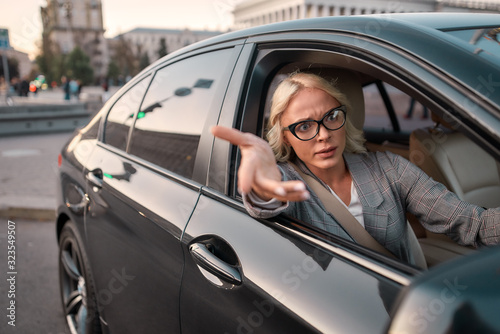 Troubles on the road. Portrait of angry business woman gesturing with hands and arguing with somebody while driving a car © Svitlana