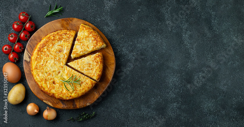 Spanish omelette with potatoes and onion, typical Spanish cuisine on a black concrete background. Tortilla espanola. Top view with copy space photo