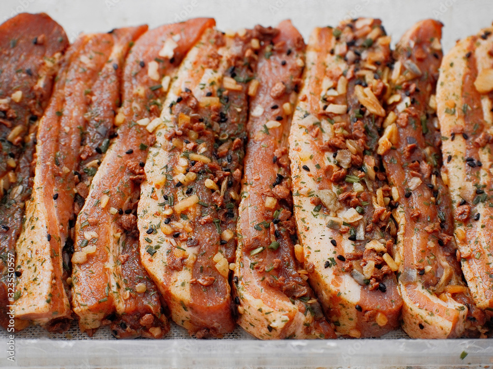 Soy sous and herbs fresh uncooked marinated pork belly slices in a plastic package. Close up. Soy sous and herbs fresh uncooked marinated pork belly slices in a plastic package. Close up.