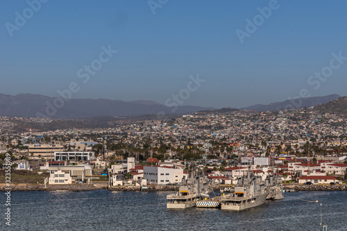 Ensenada, Mexico - January 17, 2012: Monasterio and Blanco gray navy vessels in port on blue bay water with cityscape in back under blue sky and hazy mountains.