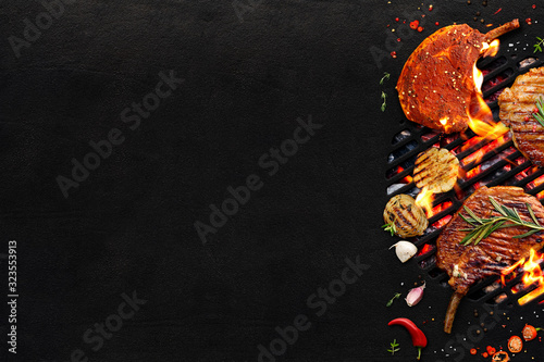 Grilled meat and vegetables on a grill plate on black background with copy space. Top view