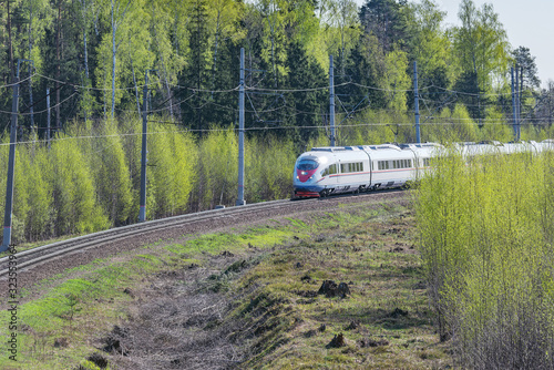 Highspeed train approaches to the station at spring day time.