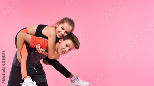Champions. Two active teenagers boy and girl having fun together after workout isolated on pink background. Fitness, sport, training, active lifestyle concept