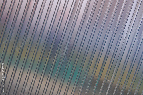 Silver tin iron wall with vertical and diagonal stripes from a metal profile of a metal sheet. Texture, background