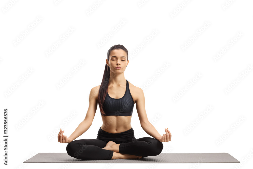 Young female practicing meditation on an exercise mat Young female practicing meditation on an exercise mat