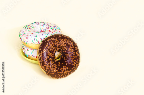 stack of donuts with white icing and a fallen chocolate doughnut on yellow background. trend in food. copy space