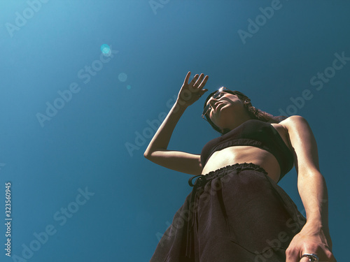 Girl on a tennis court The girl in black sportswear with sunglasses is looking at the sun Photo with copy space in bottom view photo